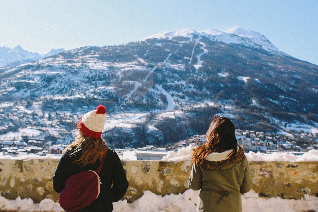 Two people overlooking a snowy mountain